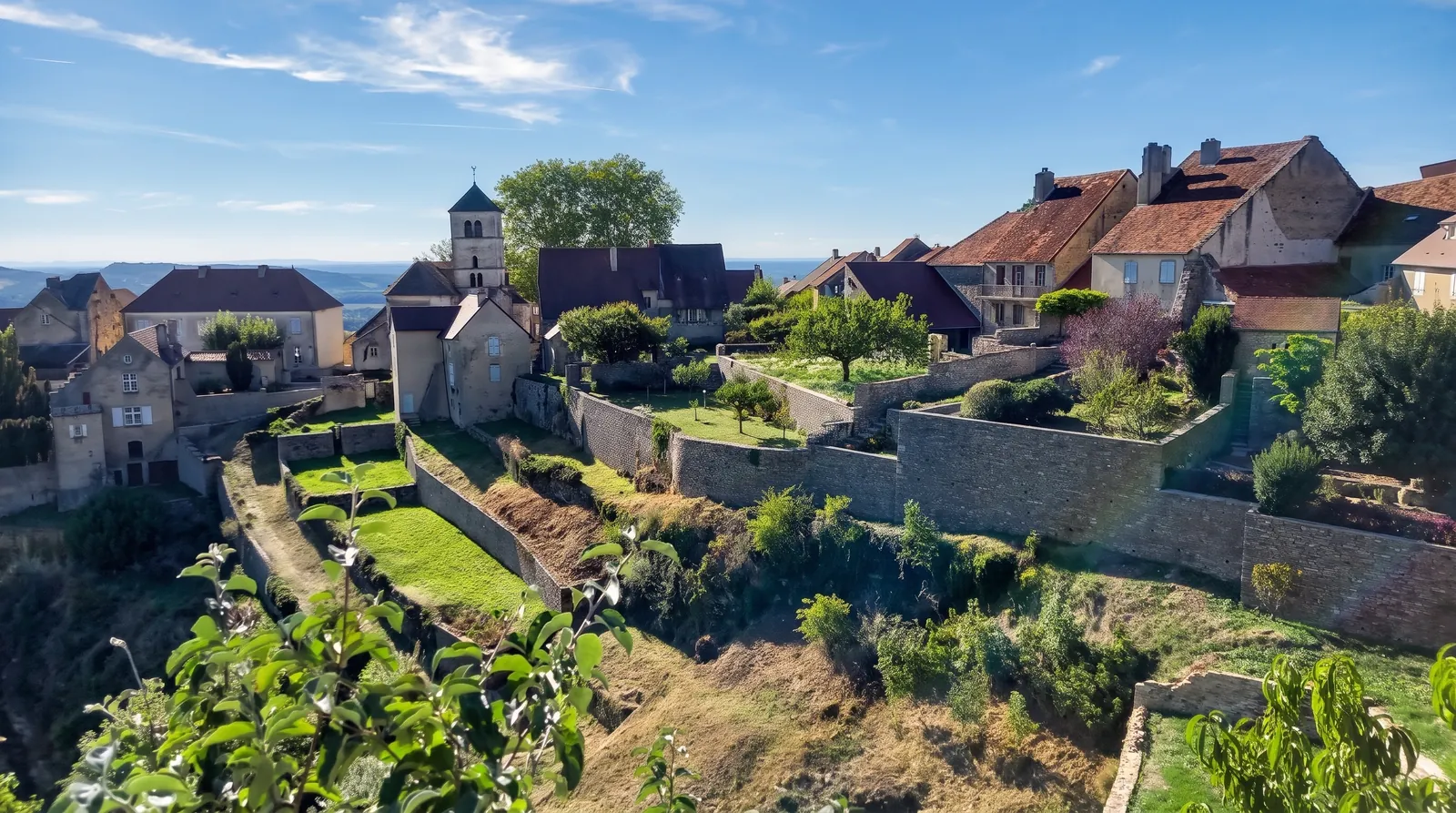 Un village perché aux toits rouges, entouré de jardins en terrasses